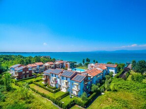 A coastal residential area with modern houses featuring solar panels, a swimming pool, and a view of the sea.