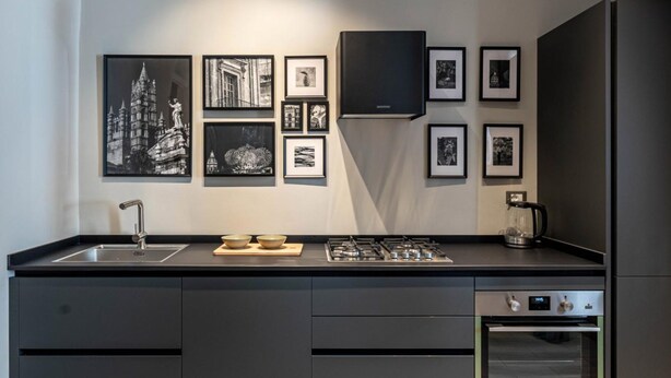 Een moderne keuken met een centraal eiland, ingebouwde apparatuur en foto's in lijsten aan de muur.