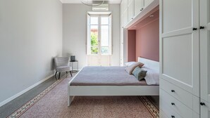 Een slaapkamer met een bed, een stoel, een bureau en een kledingkast.
