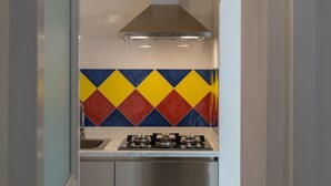 A compact kitchen with a gas stove, a stainless steel range hood, and a colorful diamond-patterned backsplash. - Isabella Apartment by Wonderful Italy (Ostuni)