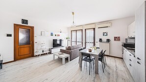 En modern lägenhet med vardagsrum, matplats och ett litet kök.