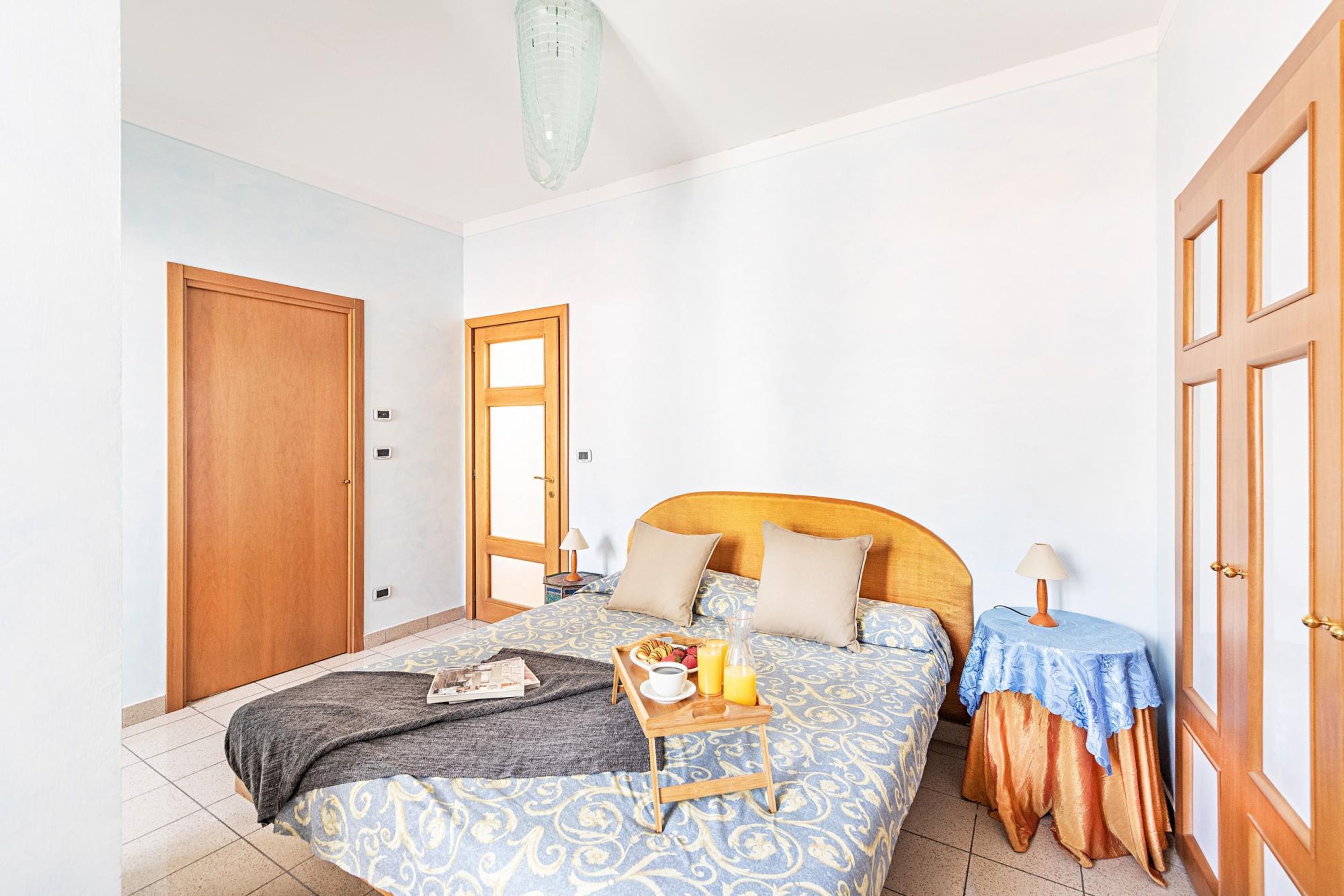 Un dormitorio con cama, mesitas de noche, una puerta y una ventana.