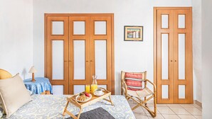 A room with a bed, a wooden wardrobe, a chair, a small table with a tray of breakfast, and a picture on the wall. - Gaudio Flat Near Ariston Theater by Wonderful Italy (Sanremo)