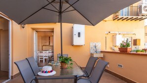 An outdoor dining area with a table, chairs, and a large umbrella. - Kalsa Apartment With Terrace by Wonderful Italy (Palermo)