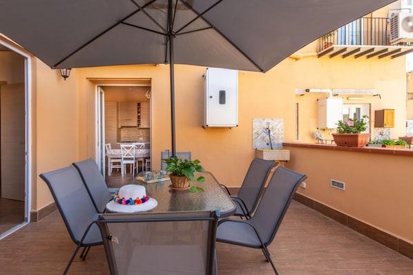 An outdoor dining area with a table, chairs, and a large umbrella.