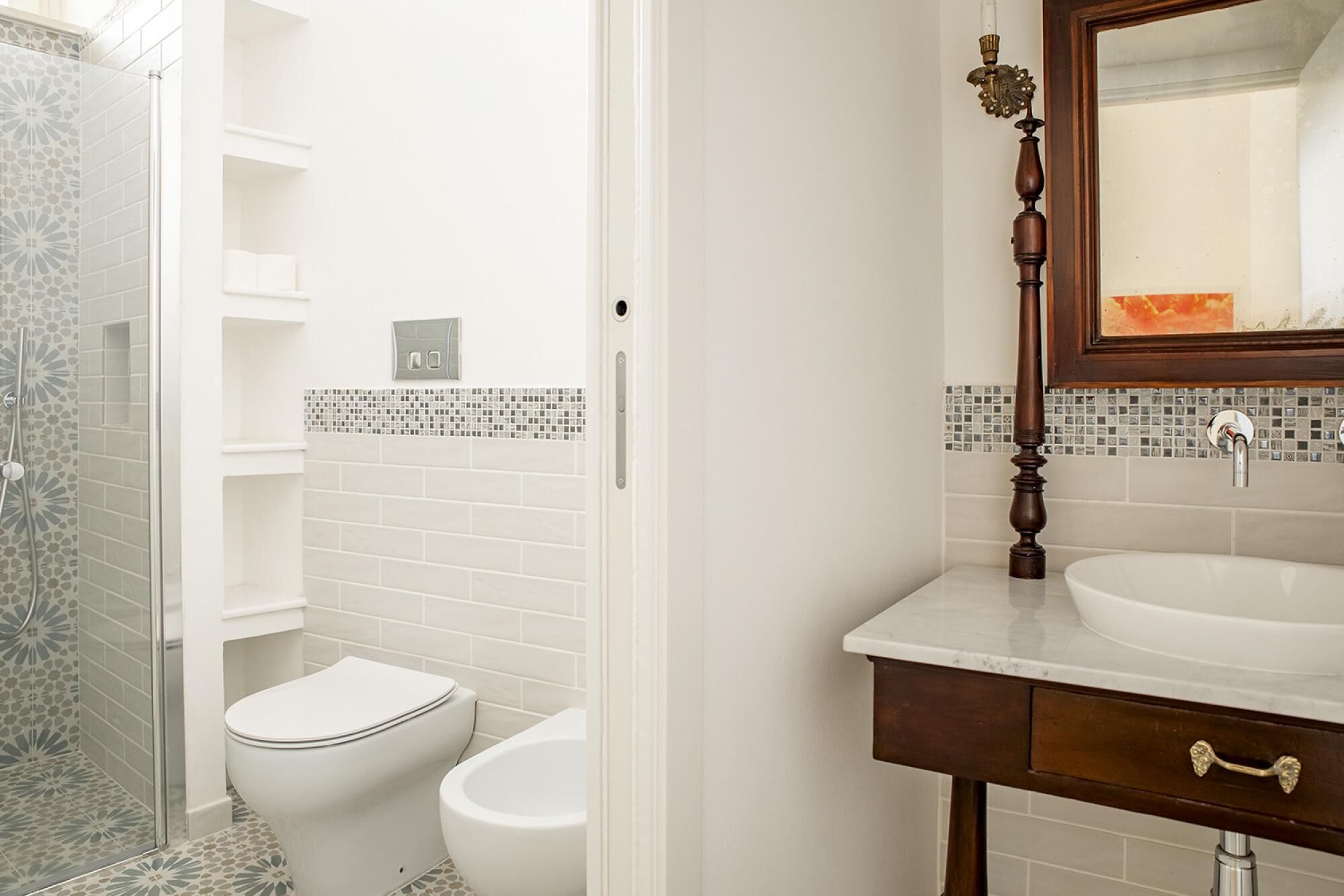 A bathroom with a toilet, bidet, and a sink with a mirror.