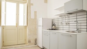 A kitchen with white cabinets, a white refrigerator, a kettle, and a sink. - Mirabella Apartment in Ortigia by Wonderful Italy (Syracuse)