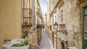 A narrow alleyway between buildings with a potted plant in the foreground. - Mirabella Apartment in Ortigia by Wonderful Italy (Syracuse)