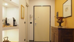 A hallway with a white door, a coffee machine, a telephone, and a decorative vase. - Guglielmo City Center Studio by Wonderful Italy (Bologna)
