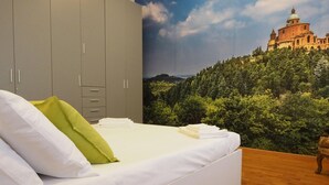 A bedroom with a bed, grey wardrobe, and a mural of a building on a hill. - Guglielmo City Center Studio by Wonderful Italy (Bologna)