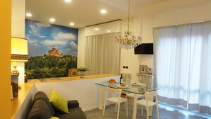 A modern living room with a sofa, a glass dining table, and a mural of a castle on the wall. - Guglielmo City Center Studio by Wonderful Italy (Bologna)