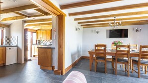 A spacious kitchen with wooden beams, a dining area with a TV, and a cozy seating area. - Family cottage near the sea - Pet Friendly sleeps 6 - 5 mins from Port Isaac (Port Isaac)