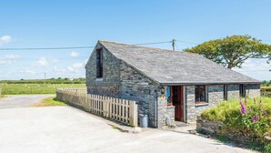 A stone cottage with a sloped roof, a wooden fence, and a grassy field in the background. - Family cottage near the sea - Pet Friendly sleeps 6 - 5 mins from Port Isaac (Port Isaac)