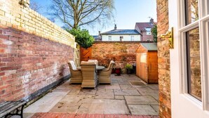Une terrasse avec des meubles en osier, un mur en briques et une petite piscine.