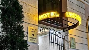 En hotelindgang med et neonskilt, en potteplante og stedmoderblomster.