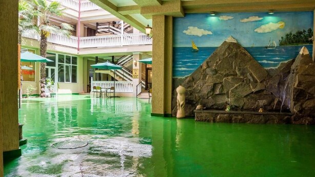 En lobby med grønt gulv, et hav-motiv som muralmaleri og en trappe.