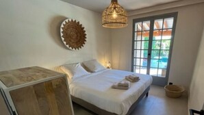 Une chambre à coucher avec un lit, un luminaire suspendu, un élément décoratif mural et une vue à travers une porte.