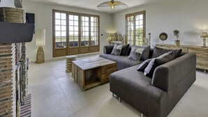 Un salon moderne avec un canapé gris, une table basse en bois et de grandes fenêtres.