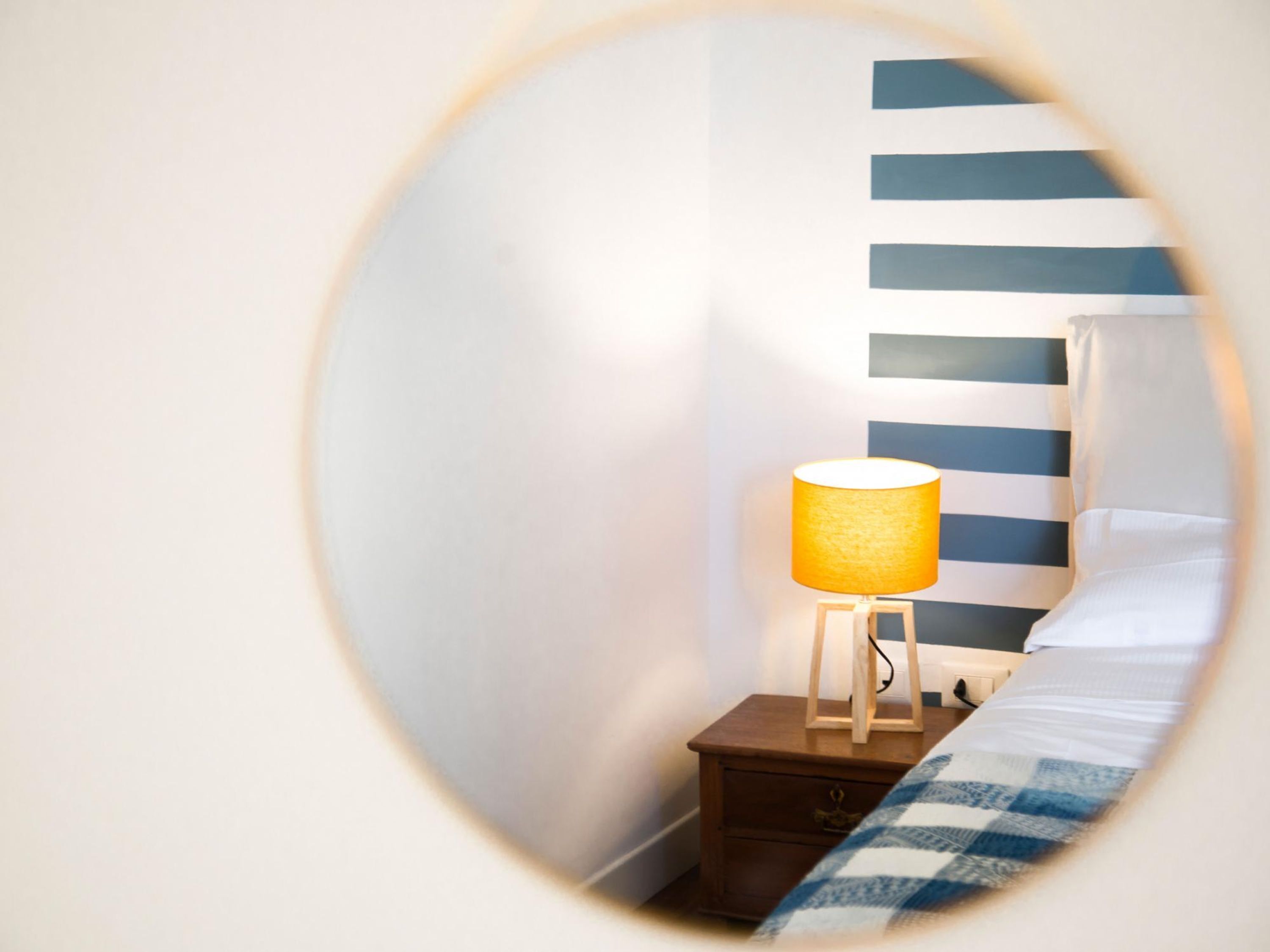A circular view of a room with a bed, a nightstand, and a lamp.