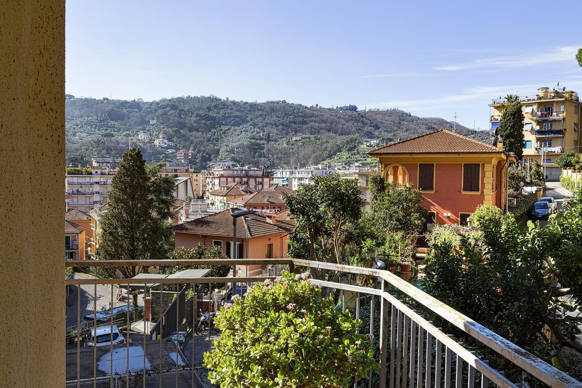 Un quartiere residenziale con un edificio giallo in evidenza, circondato da aree verdi e altre case.