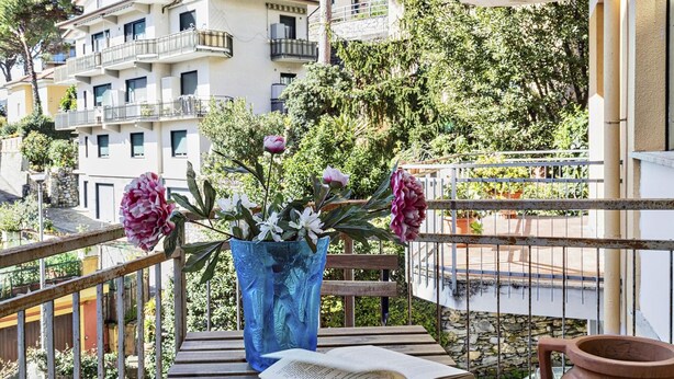A balcony with a blue vase of flowers, a book, and a terracotta pot. - Una Terrazza su Rapallo by Wonderful Italy (Rapallo)