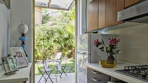 A kitchen with a gas stove, a refrigerator, and a dining area with chairs and a table. - Una Terrazza su Rapallo by Wonderful Italy (Rapallo)