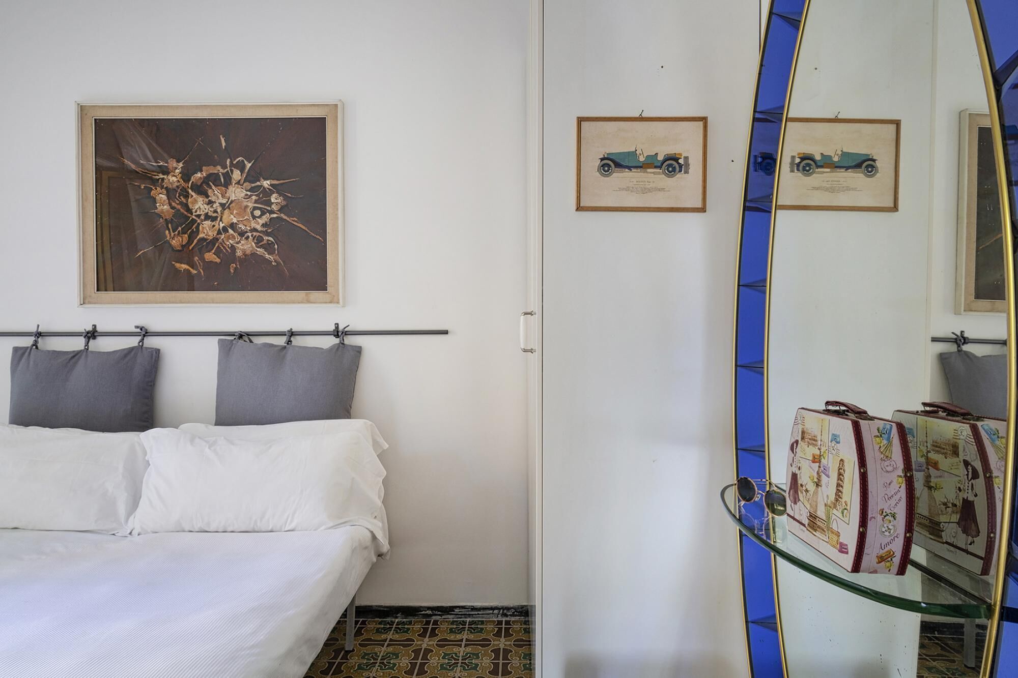 Un dormitorio con cama, un espejo grande y dos cuadros en la pared.
