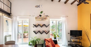 A living room with a sofa, a TV, a bookshelf, and a plant.
