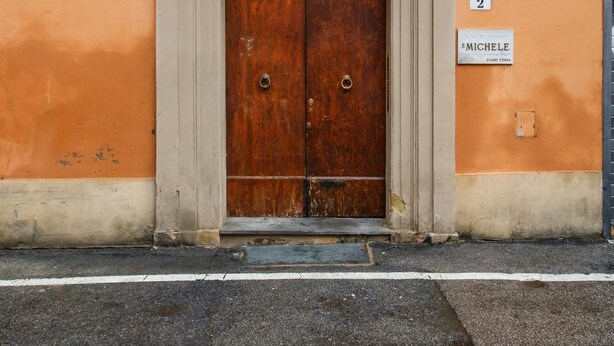 A building facade with a wooden double door, a balcony with metal railings, and a sign indicating 'Piazza San Michele'. - San Michele Apartments - Lignum by Wonderful Italy (Bologna)