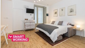 Une chambre à coucher avec un lit, des tables de chevet, une télévision et des œuvres d’art accrochées au mur.
