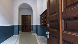 Un couloir doté d’un sol en marbre, une porte en bois avec une boîte aux lettres, et une porte double également équipée d’une boîte aux lettres.