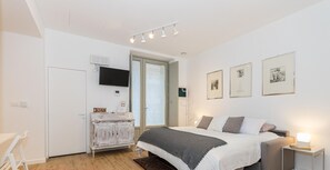 Ein Schlafzimmer mit einem Bett, Nachttischen, einem Fernseher und Kunstwerken an der Wand.