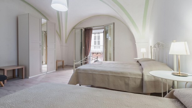 A hotel room with two beds, a small table, a bench, and a view of the outside balcony. - Apartment Manzoni 40 by Wonderful Italy (Catania)