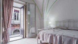 A bedroom with a bed, a nightstand, a lamp, and a view of the outside balcony. - Apartment Manzoni 40 by Wonderful Italy (Catania)