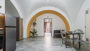 A spacious kitchen with a refrigerator, a dining area with a table and chairs, and a potted plant. - Apartment Manzoni 40 by Wonderful Italy (Catania)