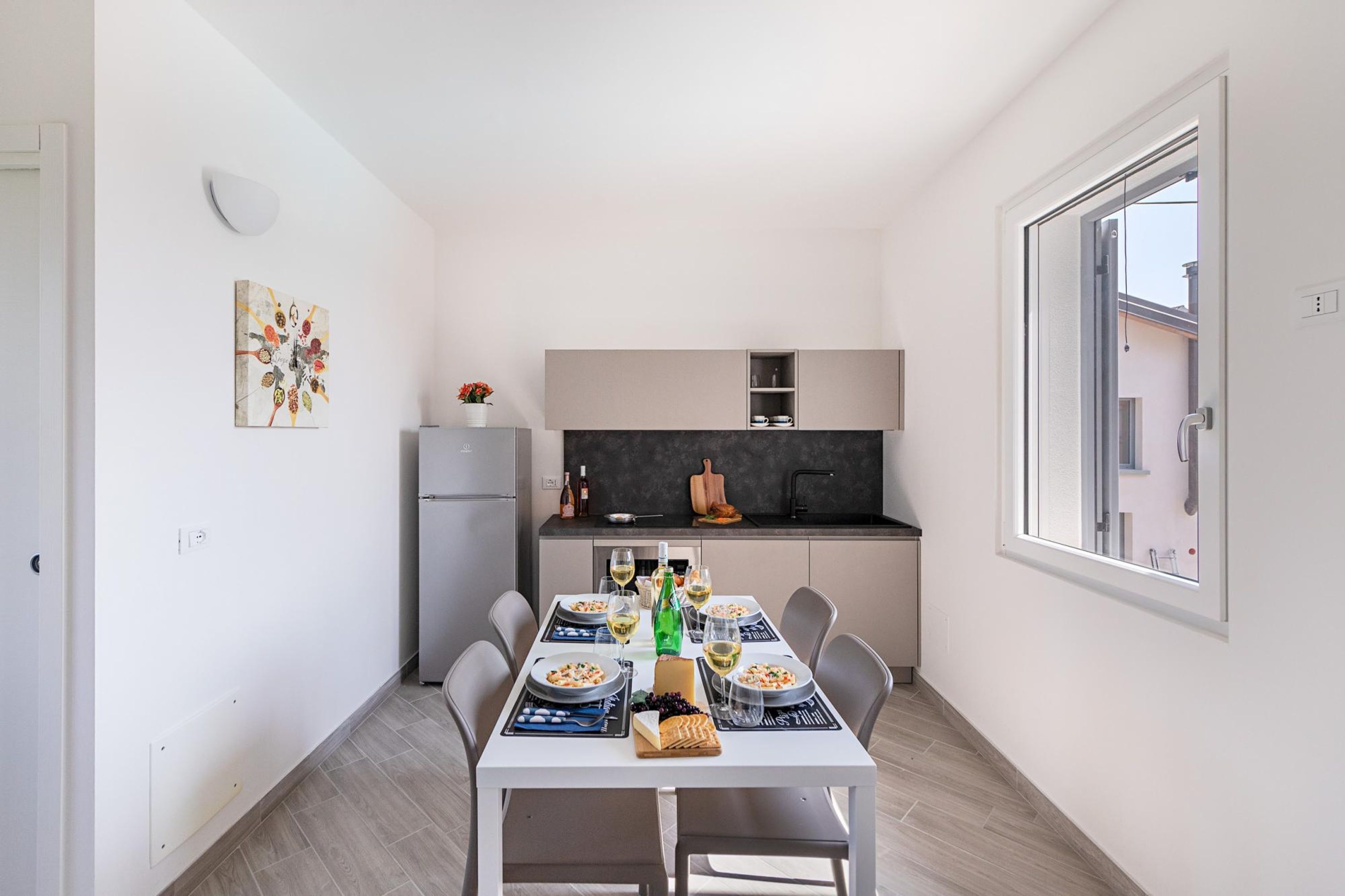 Una cocina moderna con comedor, paredes blancas y una ventana.