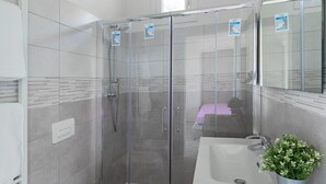 A modern bathroom with a glass-enclosed shower, a toilet, and a sink with a potted plant. - San Carlo Borromeo 3 by Wonderful Italy (Soiano del Lago)