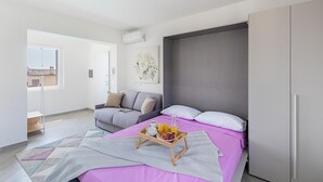 A modern bedroom with a large bed, a grey wardrobe, and a window with a view of buildings. - San Carlo Borromeo 3 by Wonderful Italy (Soiano del Lago)
