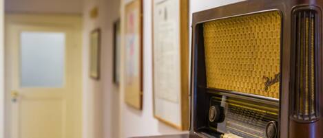 A vintage radio on a wooden table in a hallway with framed pictures on the wall.
