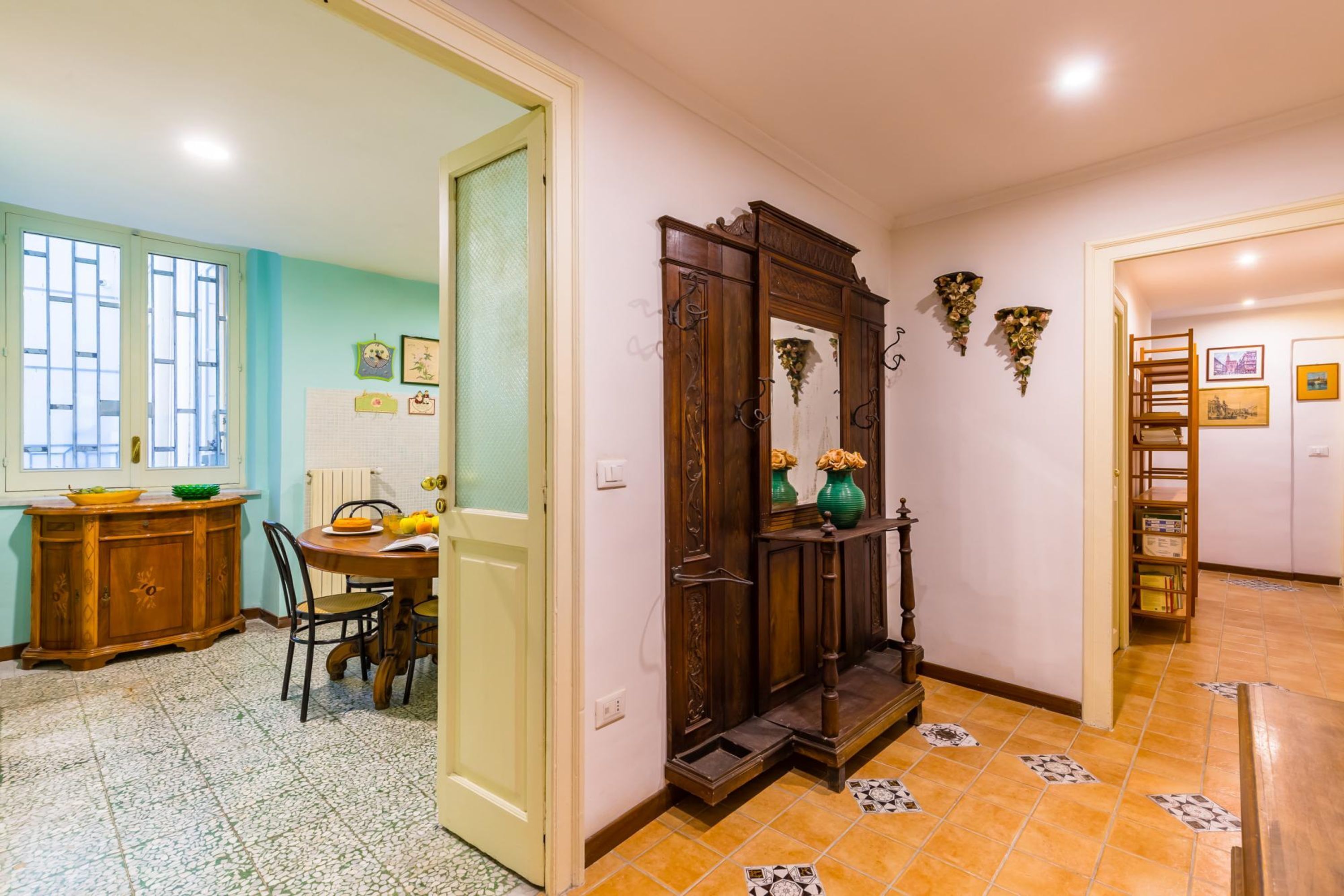 Un comedor con una mesa y sillas de madera, un armario con un cuenco, y un espejo con adornos decorativos.