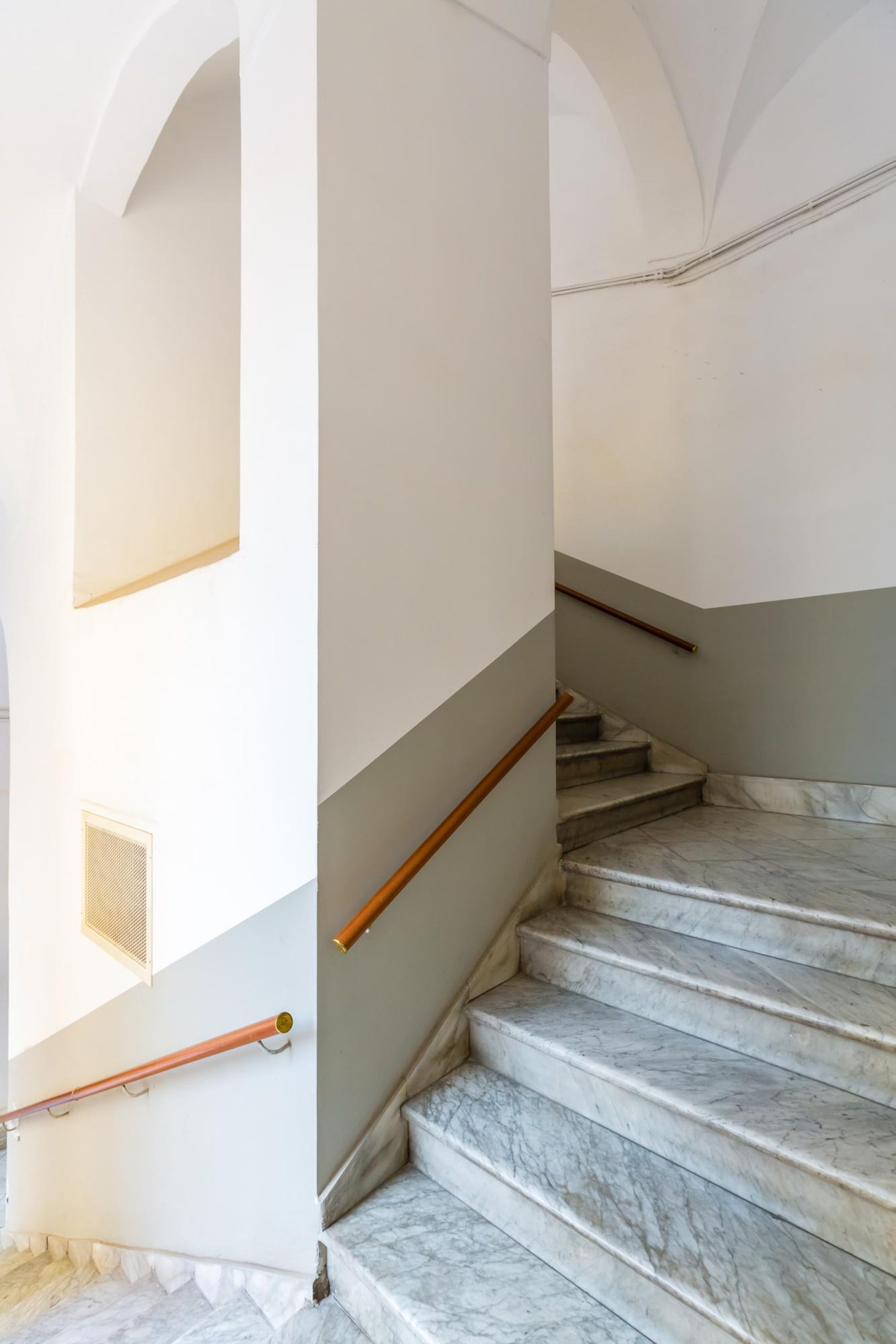A staircase with marble steps and wooden handrails, leading to an upper floor.