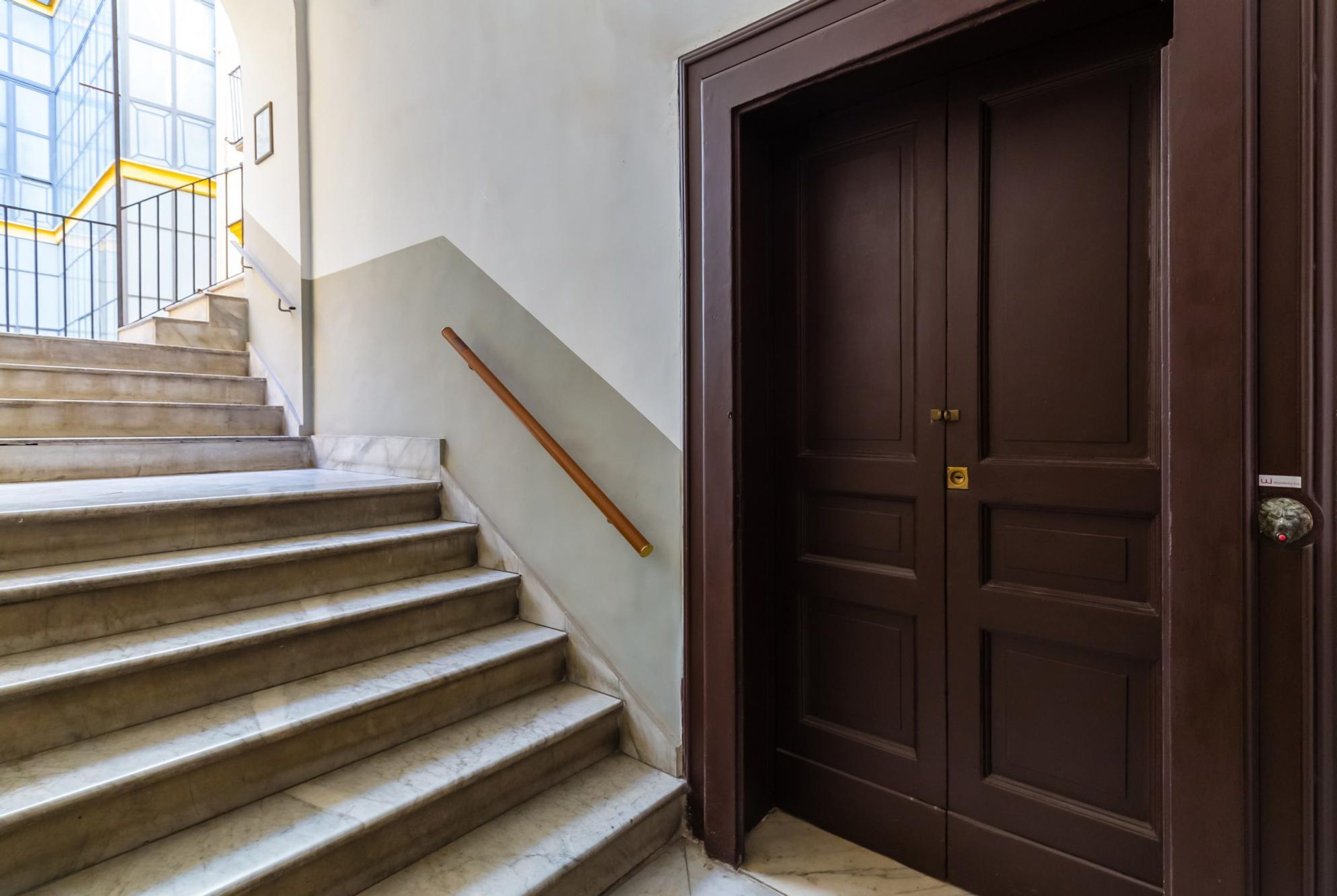 Un escalier aux marches de marbre menant à une porte en bois sombre.