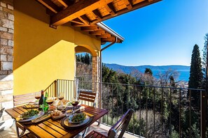 Een balkon met een eettafel, met uitzicht op een prachtig landschap met bergen en bomen.