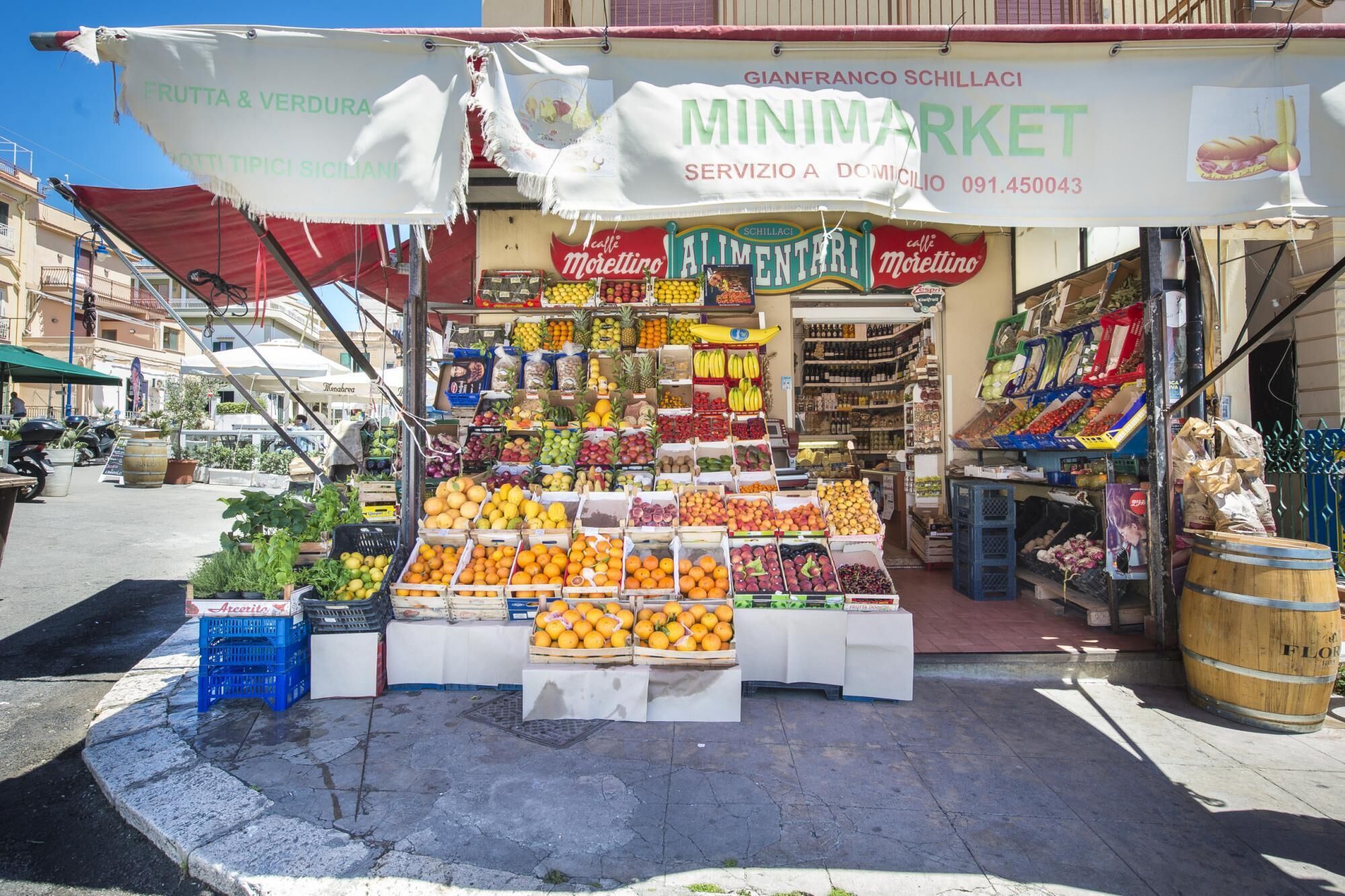 Una bancarella di frutta e verdura con una varietà di prodotti esposti in scatole e casse.