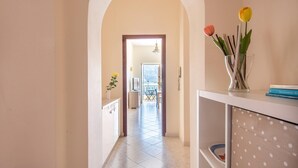 A hallway with a tiled floor leading to a balcony with a view of mountains.