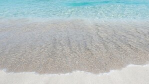 A beach with clear turquoise water and a sandy shore.