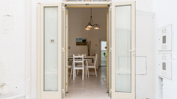 A doorway leading into a room with a dining table and chairs, a hanging light fixture, and a painting on the wall. - Casetta Biancapietra by Wonderful Italy (Ostuni)