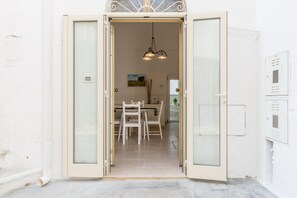 A doorway leading into a room with a dining table and chairs, a hanging light fixture, and a painting on the wall. - Casetta Biancapietra by Wonderful Italy (Ostuni)