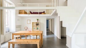 A spacious loft-style apartment with a high ceiling, a wooden dining table, and a built-in bench. - Casa Roma al Centro di Palermo by Wonderful Italy (Palermo)