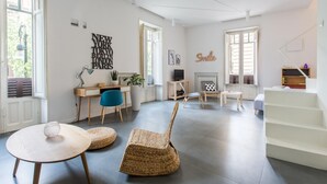 A spacious living room with a modern design, featuring a large window, a fireplace, and a staircase. - Casa Roma al Centro di Palermo by Wonderful Italy (Palermo)